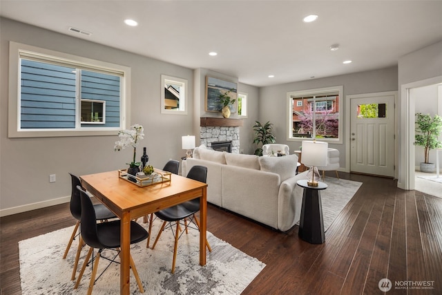 living area with baseboards, recessed lighting, a stone fireplace, and dark wood-type flooring