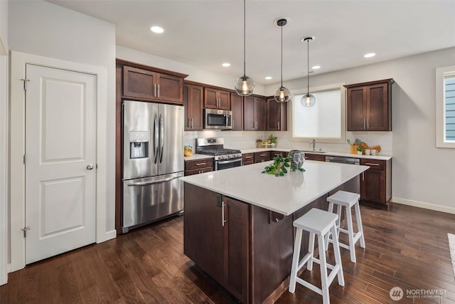 kitchen featuring dark wood finished floors, dark brown cabinetry, a breakfast bar, and stainless steel appliances