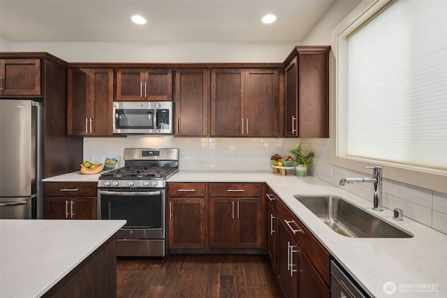 kitchen with backsplash, dark wood-style flooring, appliances with stainless steel finishes, a sink, and recessed lighting