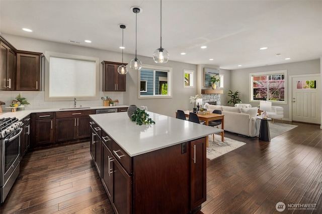 kitchen featuring a sink, light countertops, stainless steel gas stove, and dark wood-type flooring
