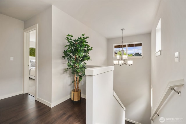 stairway with baseboards, an inviting chandelier, and wood finished floors