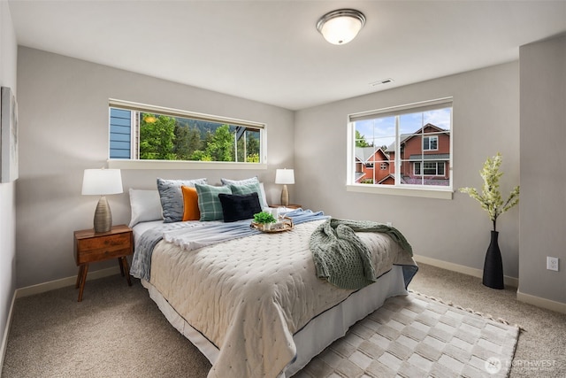 bedroom with visible vents, carpet, baseboards, and multiple windows