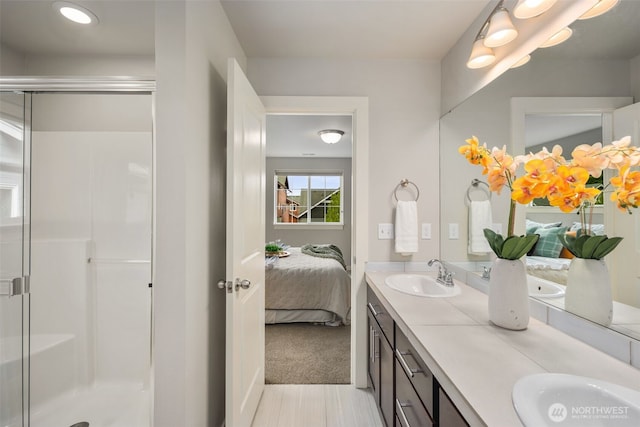ensuite bathroom with double vanity, a sink, and a stall shower