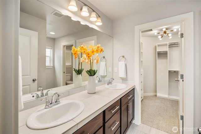 bathroom with double vanity, a sink, and toilet