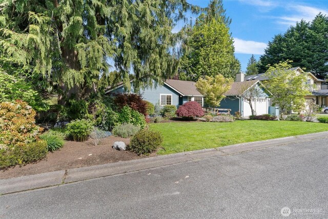 ranch-style home featuring a garage and a front lawn