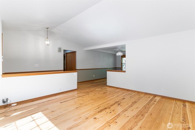 empty room featuring baseboards, vaulted ceiling, and hardwood / wood-style floors