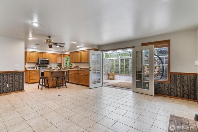 kitchen with a ceiling fan, appliances with stainless steel finishes, plenty of natural light, and a breakfast bar