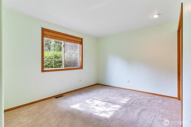 carpeted empty room with visible vents and baseboards