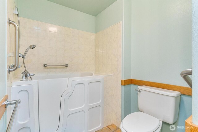 full bath with a bathing tub, toilet, and tile patterned floors
