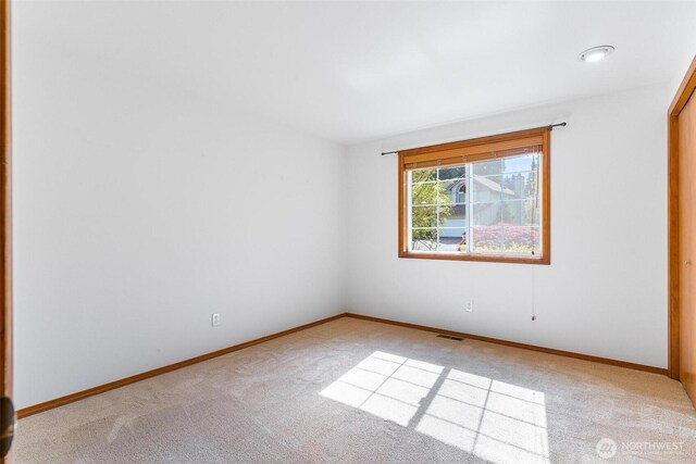 empty room featuring carpet floors, baseboards, and visible vents