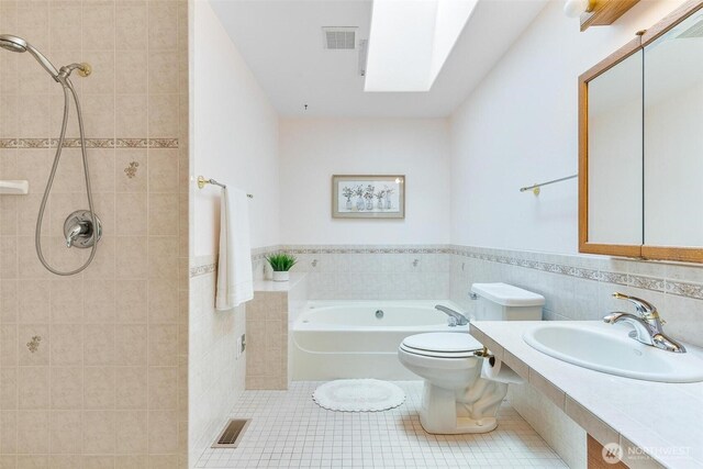 bathroom with a garden tub, visible vents, tile walls, tile patterned floors, and a sink