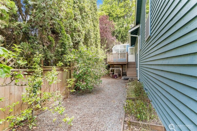 view of yard with fence, a wooden deck, and stairs