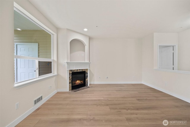 unfurnished living room with a fireplace, recessed lighting, baseboards, light wood-type flooring, and visible vents