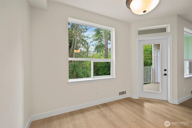 doorway featuring light wood-style floors, baseboards, and visible vents