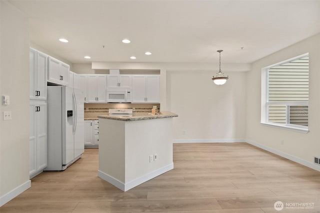 kitchen with white appliances, light wood-style floors, recessed lighting, white cabinets, and light stone counters