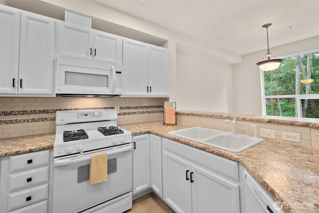 kitchen with white cabinets, a sink, white appliances, light countertops, and tasteful backsplash