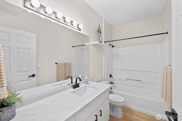 bathroom featuring toilet, bathing tub / shower combination, wood finished floors, and vanity