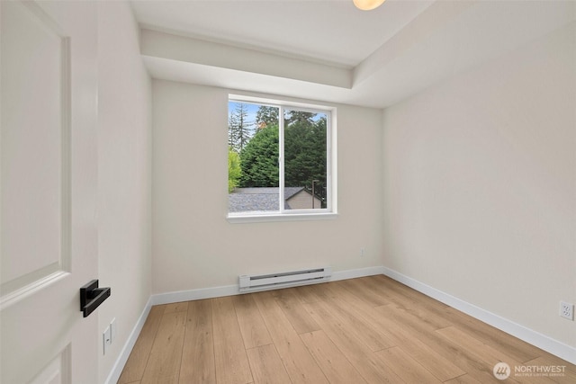empty room featuring light wood-style floors, baseboards, and a baseboard heating unit