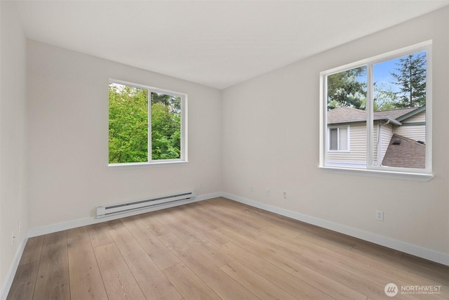 empty room with baseboards, a baseboard radiator, wood-type flooring, and a wealth of natural light