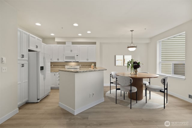 kitchen featuring light stone counters, light wood finished floors, white appliances, recessed lighting, and white cabinetry
