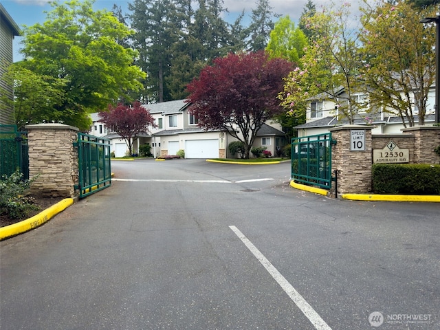 view of road with street lighting, curbs, a gated entry, and a residential view