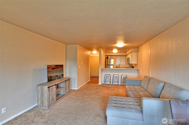 living area featuring carpet flooring, baseboards, and a textured wall