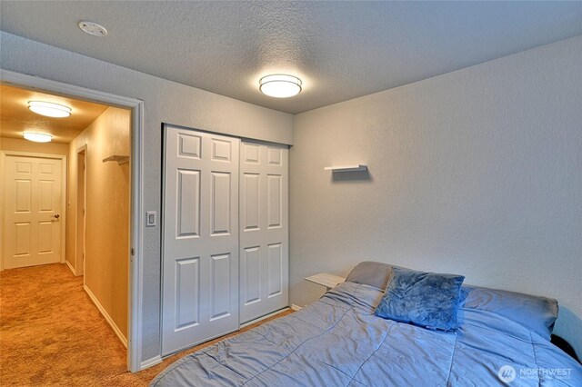 carpeted bedroom with a textured ceiling, a textured wall, and a closet
