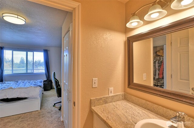 bathroom with a textured ceiling, a textured wall, and vanity