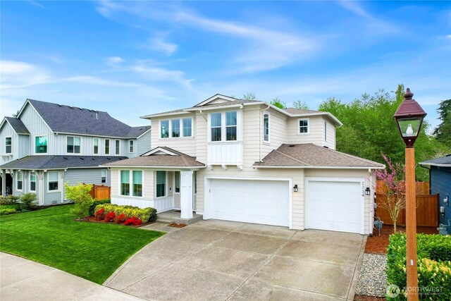 traditional-style home featuring fence, a front yard, roof with shingles, concrete driveway, and an attached garage