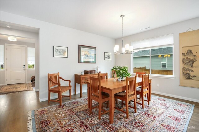 dining room featuring an inviting chandelier, baseboards, wood finished floors, and visible vents