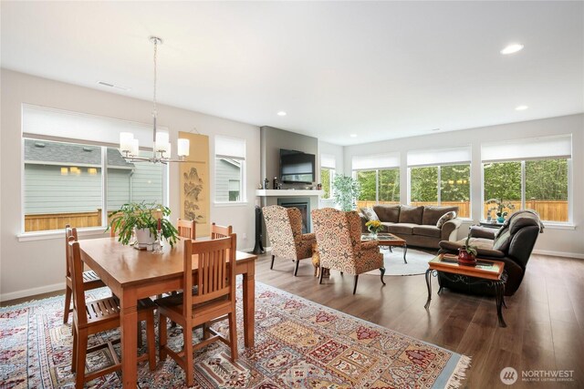 dining room featuring a notable chandelier, a fireplace, recessed lighting, baseboards, and wood finished floors