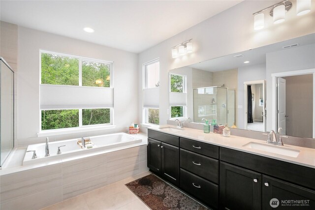 bathroom with double vanity, a shower stall, a sink, and a garden tub