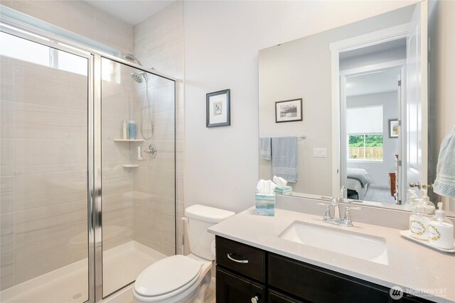 ensuite bathroom with vanity, ensuite bathroom, a stall shower, and toilet