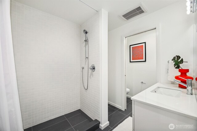 115 E Allison St, Seattle, WA 98102 - bathroom featuring visible vents, tile patterned flooring, a tile shower, vanity, and baseboards