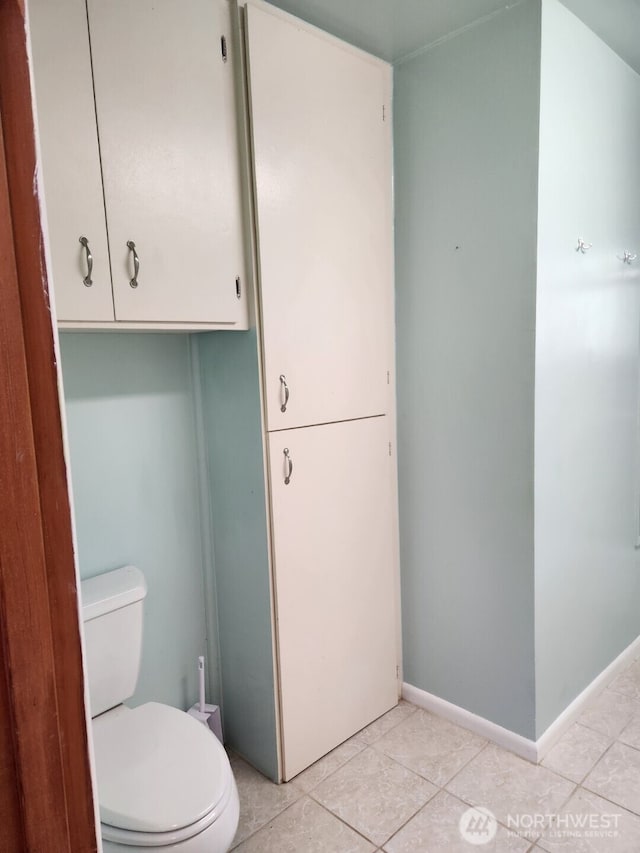 bathroom with baseboards, tile patterned floors, and toilet