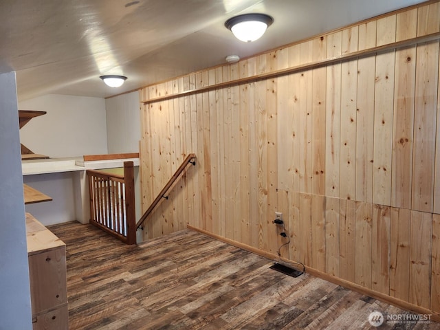 basement with wooden walls, wood finished floors, and visible vents