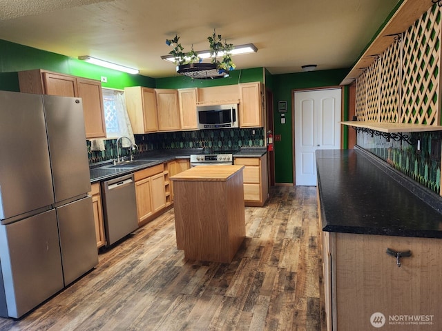 kitchen with a sink, light brown cabinets, stainless steel appliances, and wood finished floors