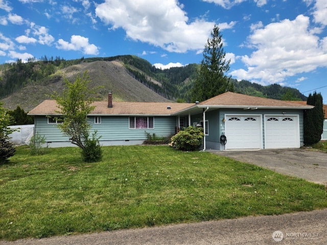 ranch-style house featuring a garage, a mountain view, concrete driveway, and a front yard