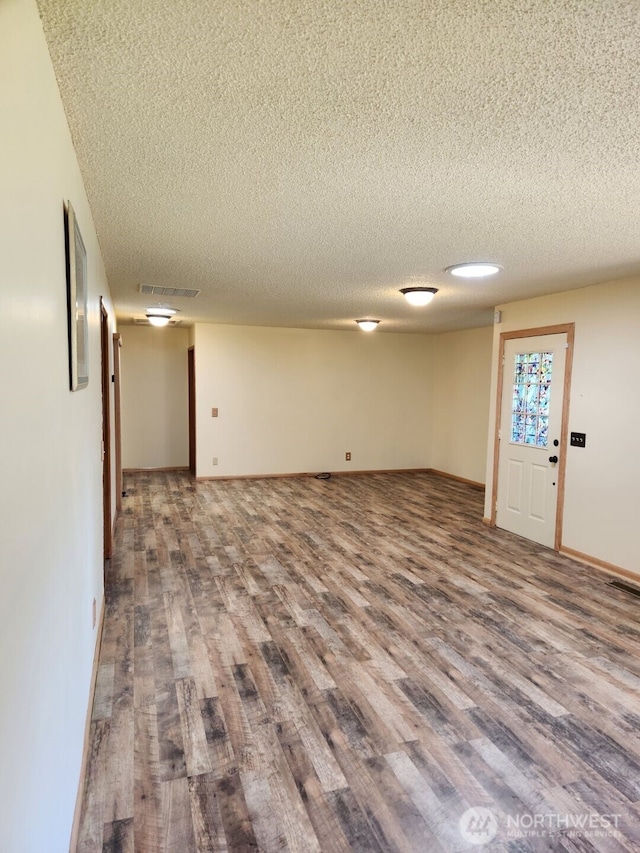 interior space with visible vents, baseboards, a textured ceiling, and wood finished floors