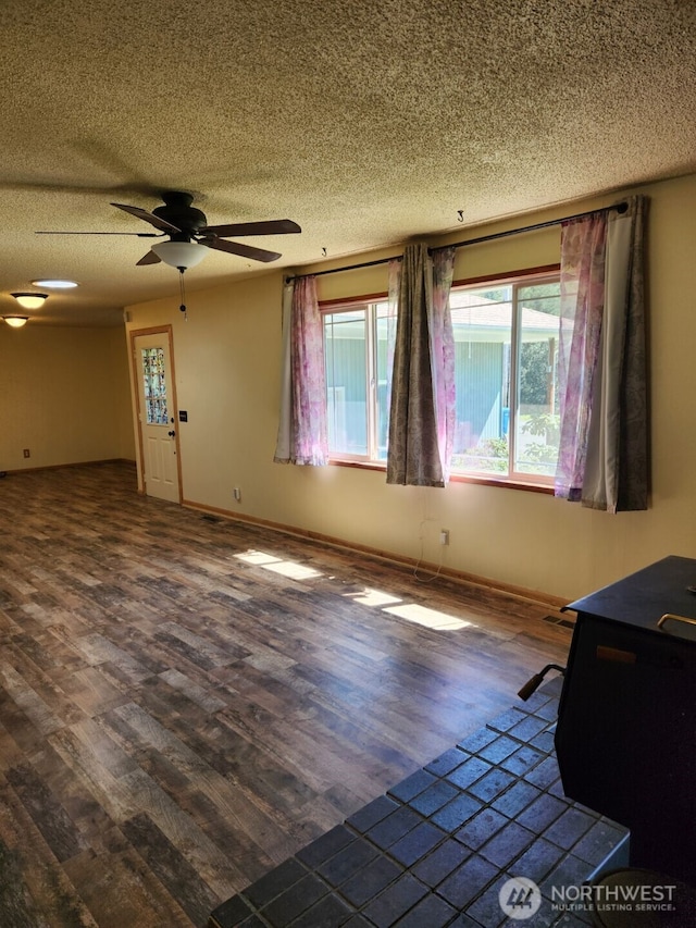 interior space with baseboards, ceiling fan, dark wood-style floors, and a textured ceiling