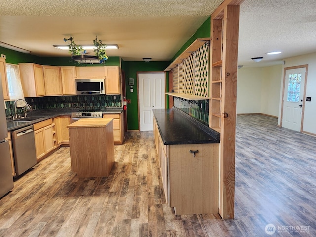 kitchen with a sink, appliances with stainless steel finishes, light brown cabinets, and light wood-style floors