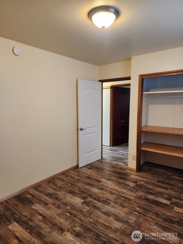 unfurnished bedroom with baseboards and dark wood-style flooring