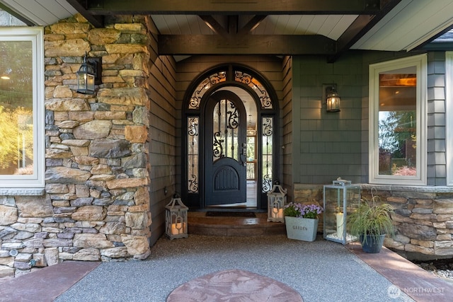entrance to property with a porch and stone siding