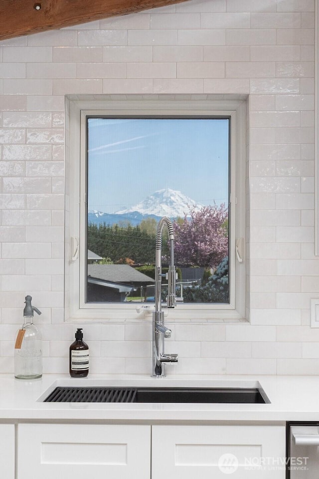 kitchen featuring white cabinets, light countertops, a sink, and tasteful backsplash