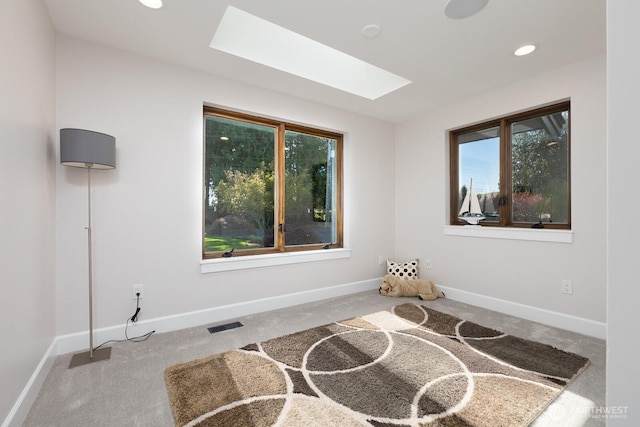 carpeted empty room featuring baseboards, recessed lighting, visible vents, and a skylight