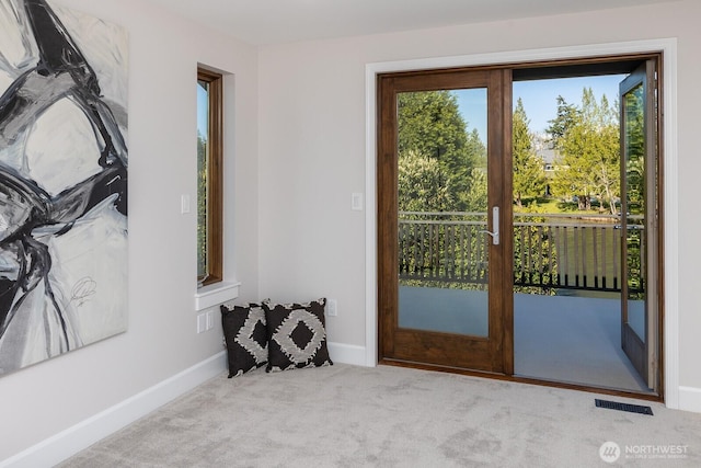 doorway to outside with a healthy amount of sunlight, baseboards, carpet flooring, and visible vents