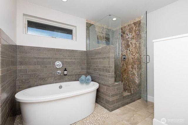 bathroom with tile walls, a soaking tub, a shower stall, and recessed lighting