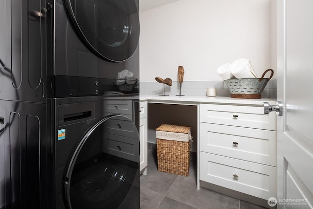 washroom with tile patterned flooring, stacked washer and clothes dryer, and cabinet space