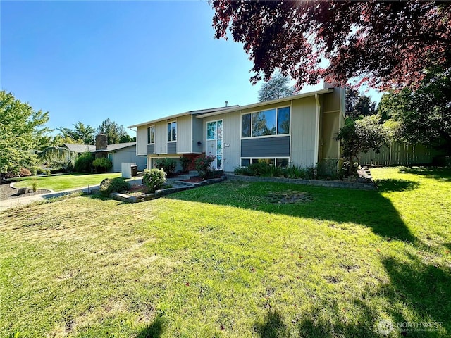 bi-level home featuring fence and a front lawn