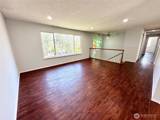 spare room with recessed lighting, a textured ceiling, dark wood finished floors, and a wealth of natural light